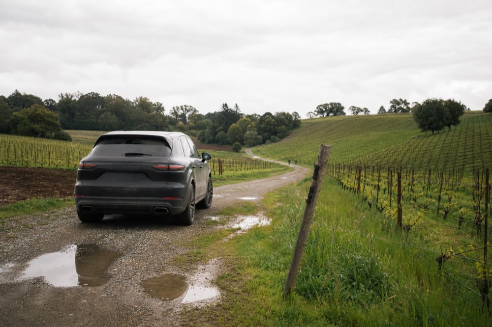 A luxury SUV waiting on a gravel drive beside rolling Sonoma vineyards, no text, no logos, no people.