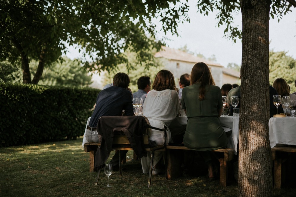Small group of guests seated at a long outdoor tasting table in a garden, no text, no logos, no people.