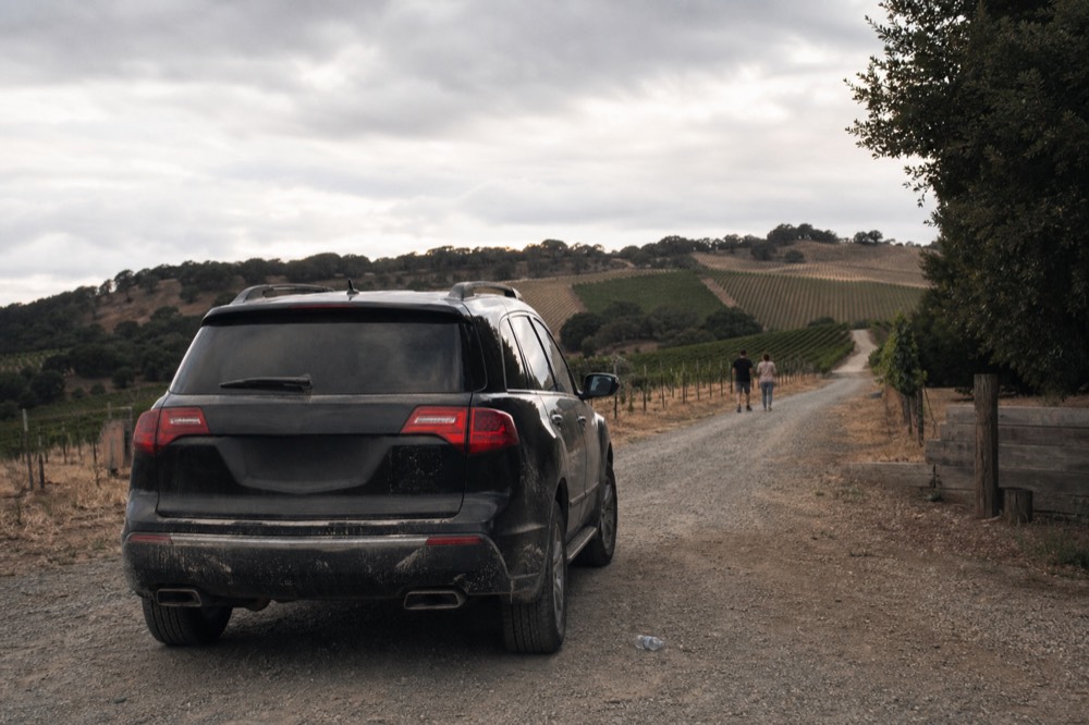 Black SUV parked on a gravel winery driveway among rolling hills, no text, no logos, no people